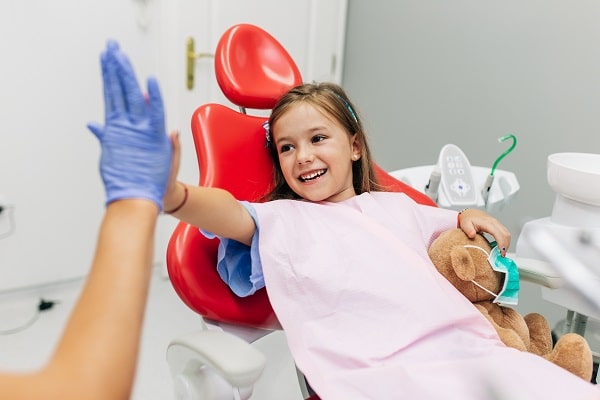 Kid in dental chair high fiving dentist - Spokane Family Dental